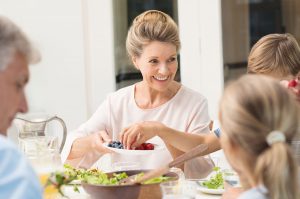 Older woman smiling and have a meal a t the table with her family.