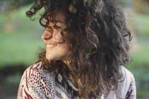Young woman with curly hair smiling and looking to the side