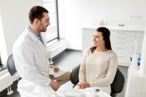 A woman sitting in a dental chair talking to her doctor