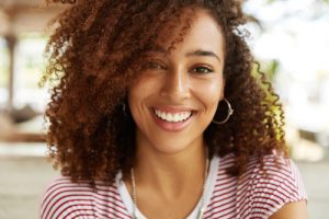 A young woman with short curly hair smiling