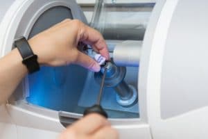 A close up of hands using a CEREC same day crowns machine