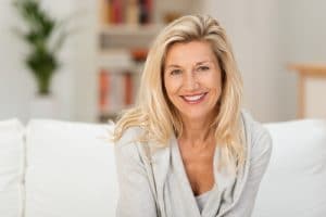 An older woman sitting on the couch smiling