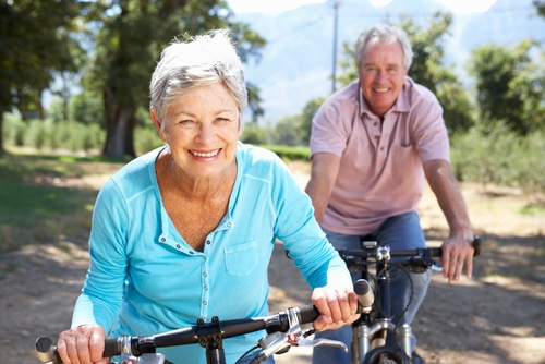 An older couple smiling and riding bikes